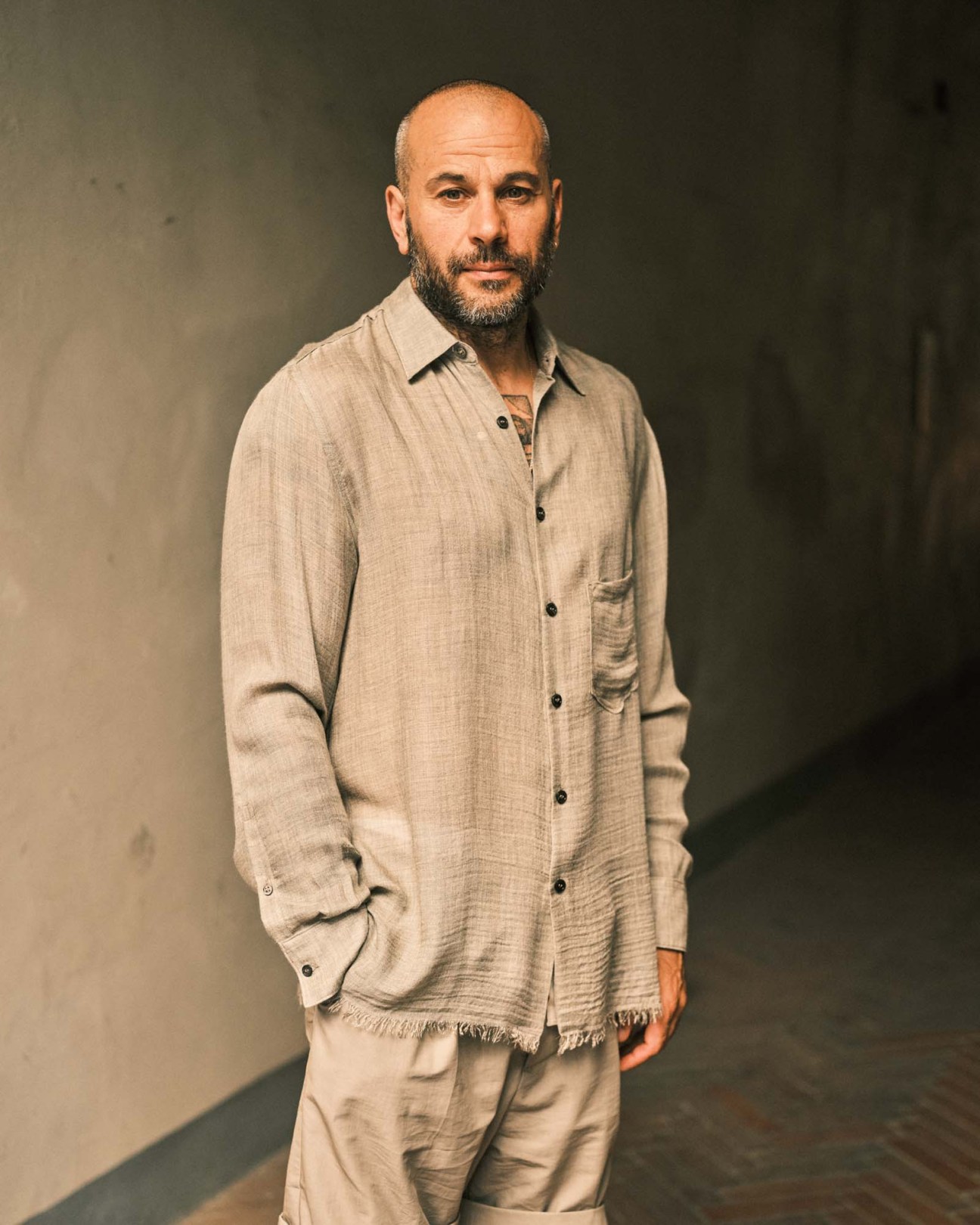 Menswear designer Federico Curradi wearing a beige linen button-up shirt with frayed hem and matching trousers.