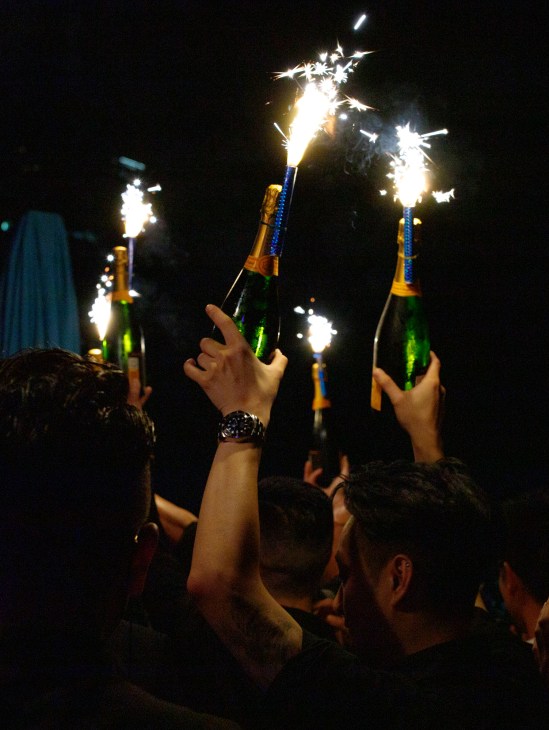 Revellers holding champagne bottles with lit sparklers at Faye nightclub in Hong Kong.