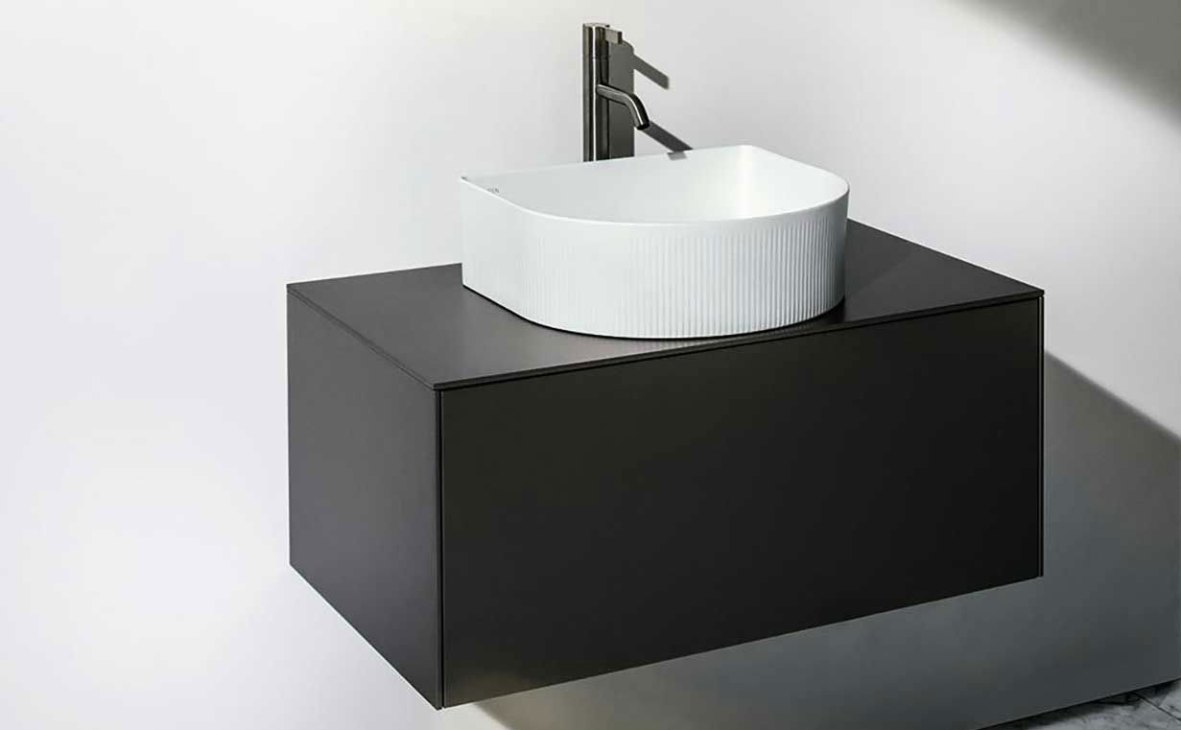 Modern white ceramic washbasin with ridged texture on black vanity cabinet with chrome faucet