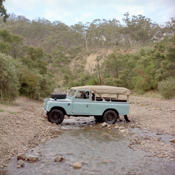 Vintage off-road vehicle crossing a rocky creek