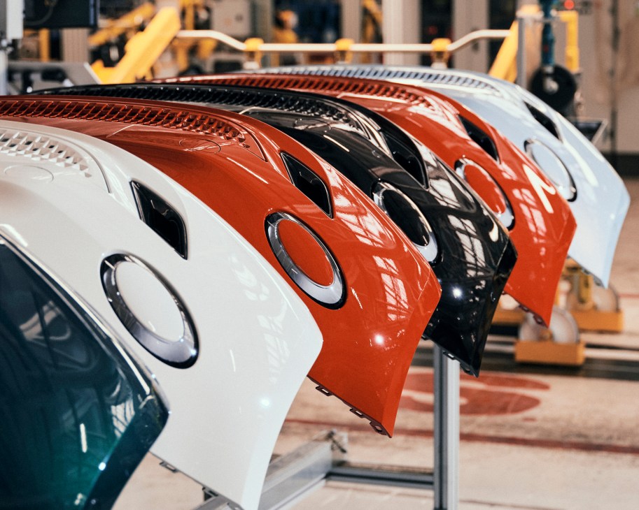 Multiple Fiat 500e car bonnets in white, red, and black lined up ready for assembly.