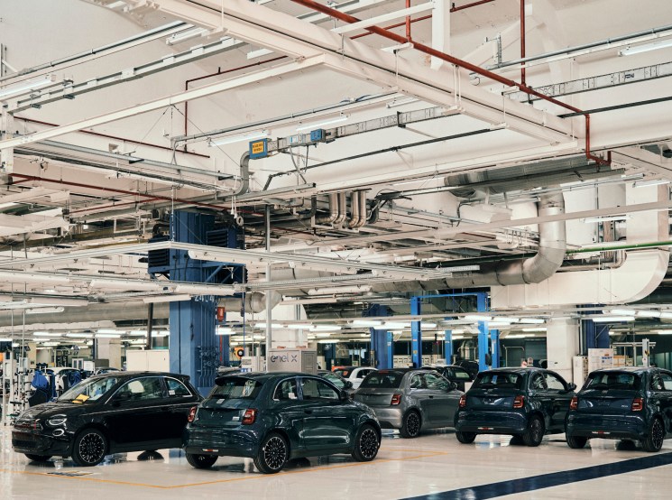 Multiple completed Fiat 500e electric cars charging at the Mirafiori manufacturing plant in Turin.