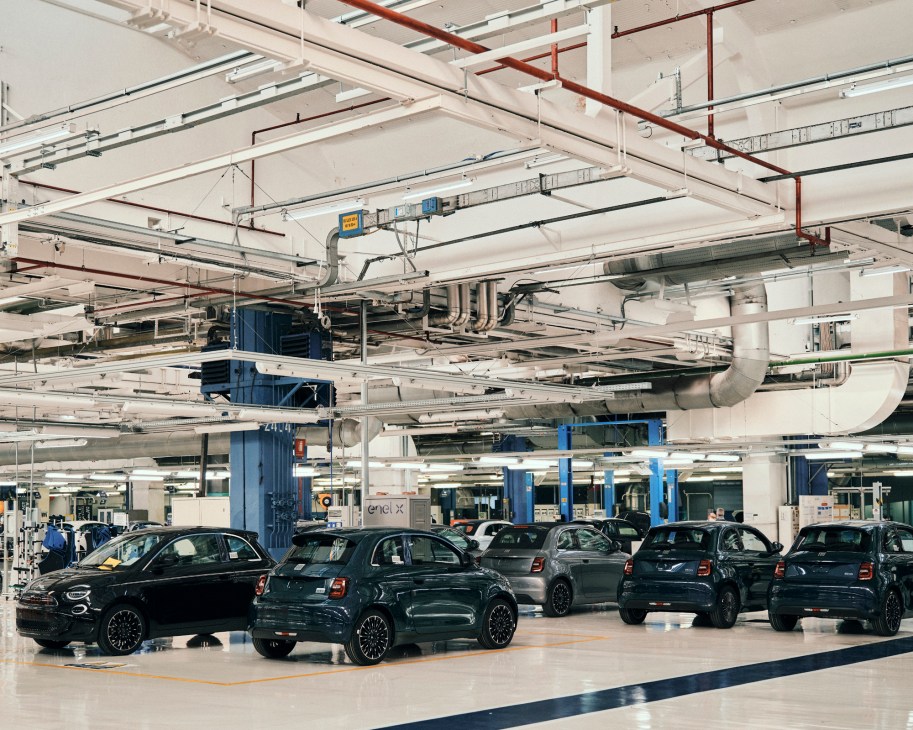 Multiple completed Fiat 500e electric cars charging at the Mirafiori manufacturing plant in Turin.