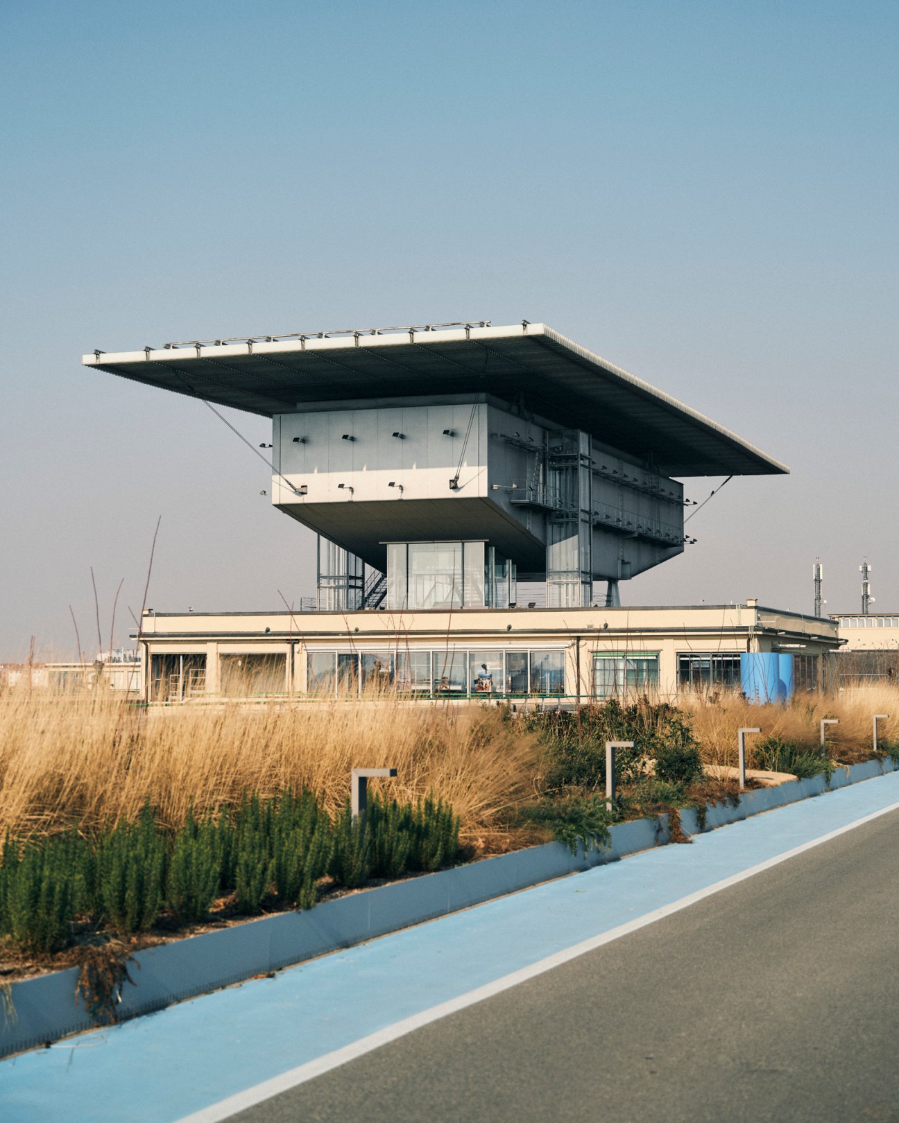 Modern building with cantilevered roof and green vegetation on rooftop overlooking marshland.