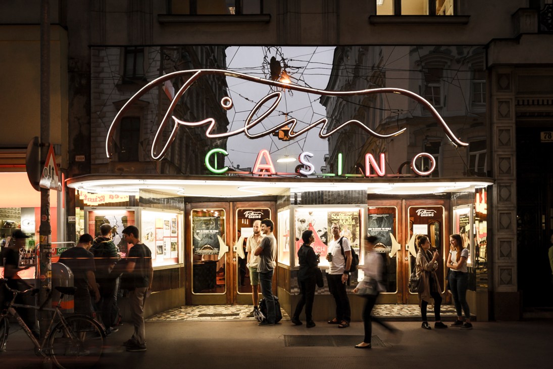 Neon-lit Filmcasino storefront with people gathered outside at night
