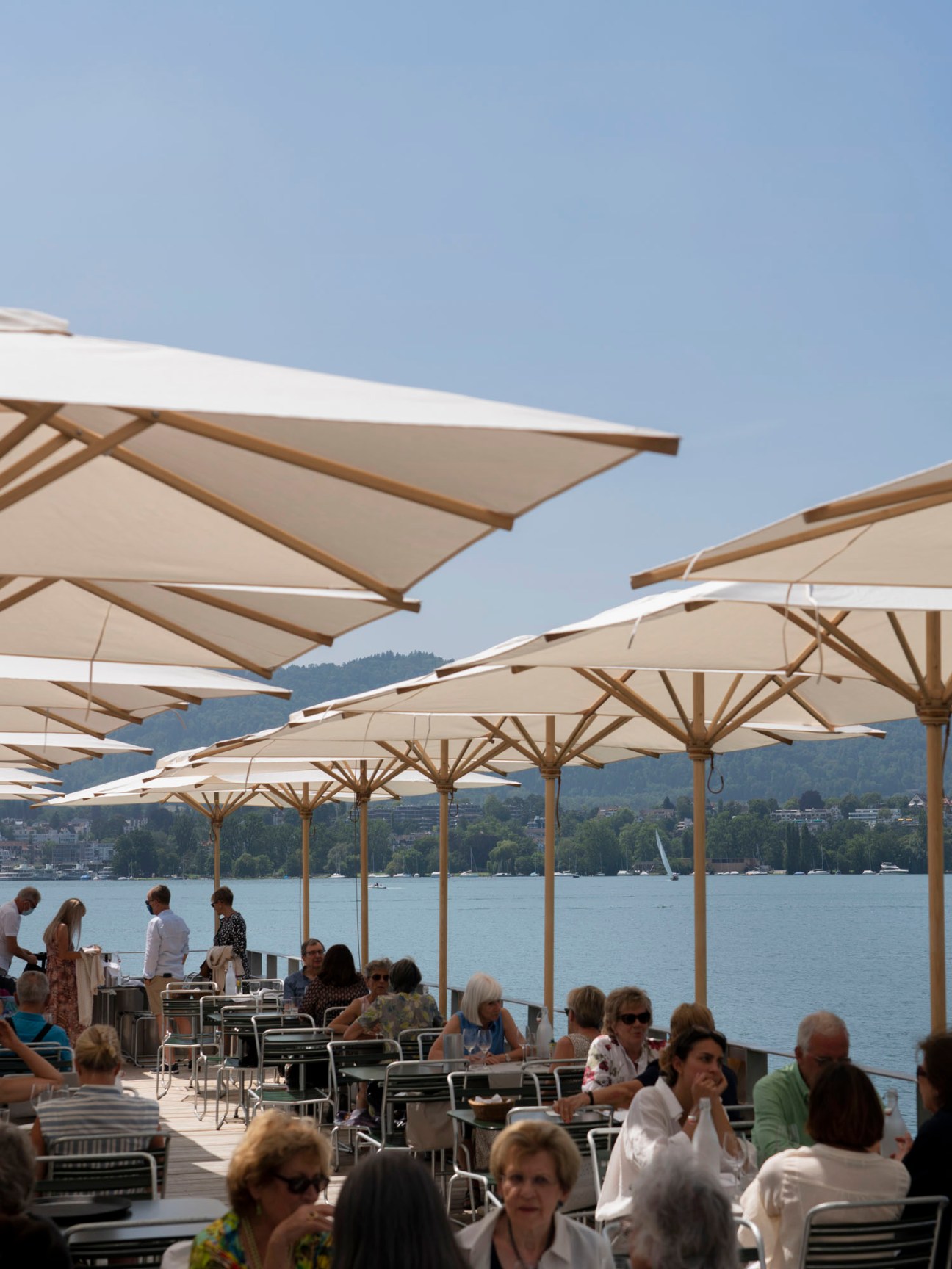 Diners seated at outdoor tables on the wooden Seeterrasse platform overlooking Lake Zürich