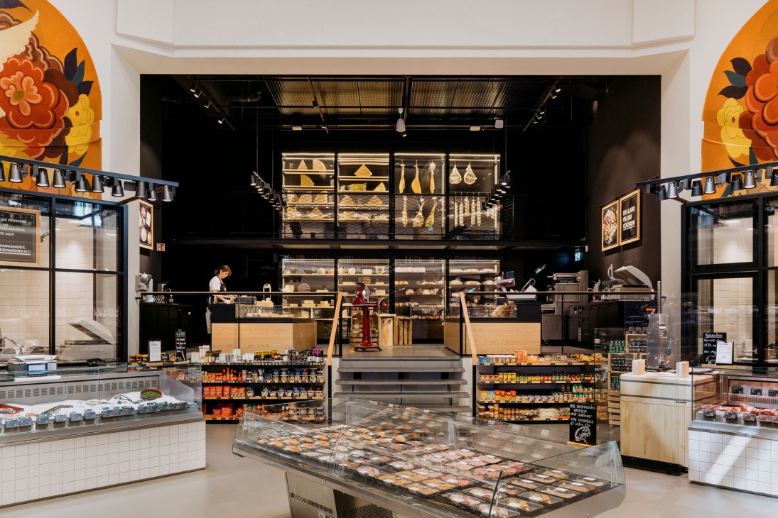 Modern supermarket interior with elevated bakery section, industrial ceiling, and multi-level layout in former theatre