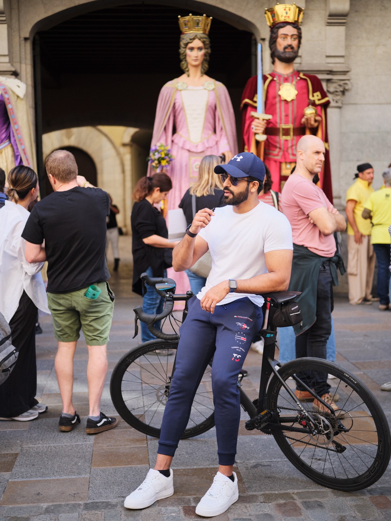 Man on bicycle in Girona's Old Town with religious statues visible behind him.