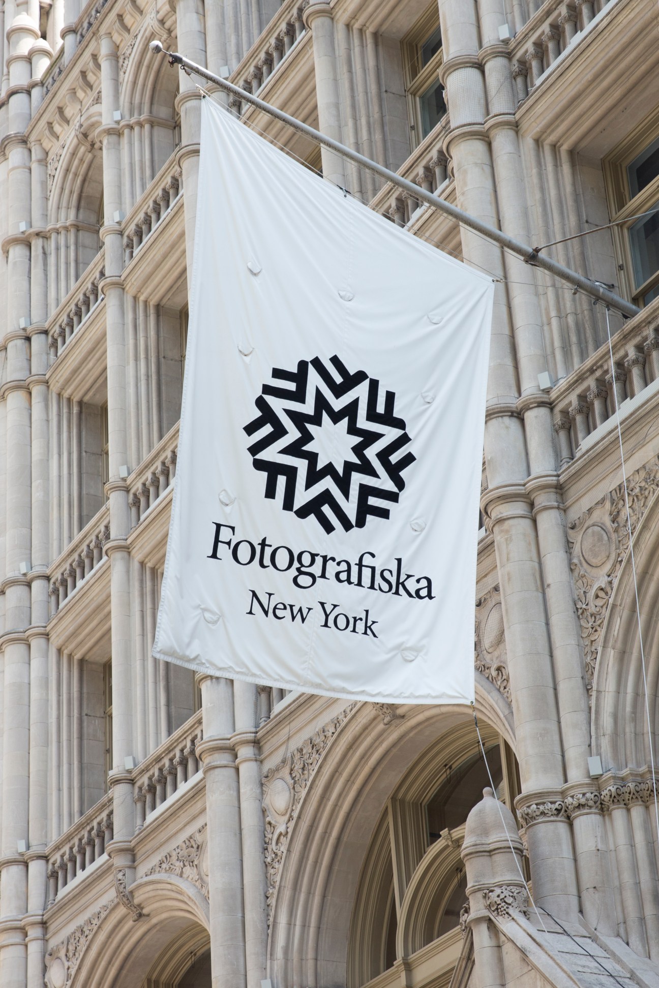White banner with Fotografiska New York logo hanging on historic stone building with classical columns