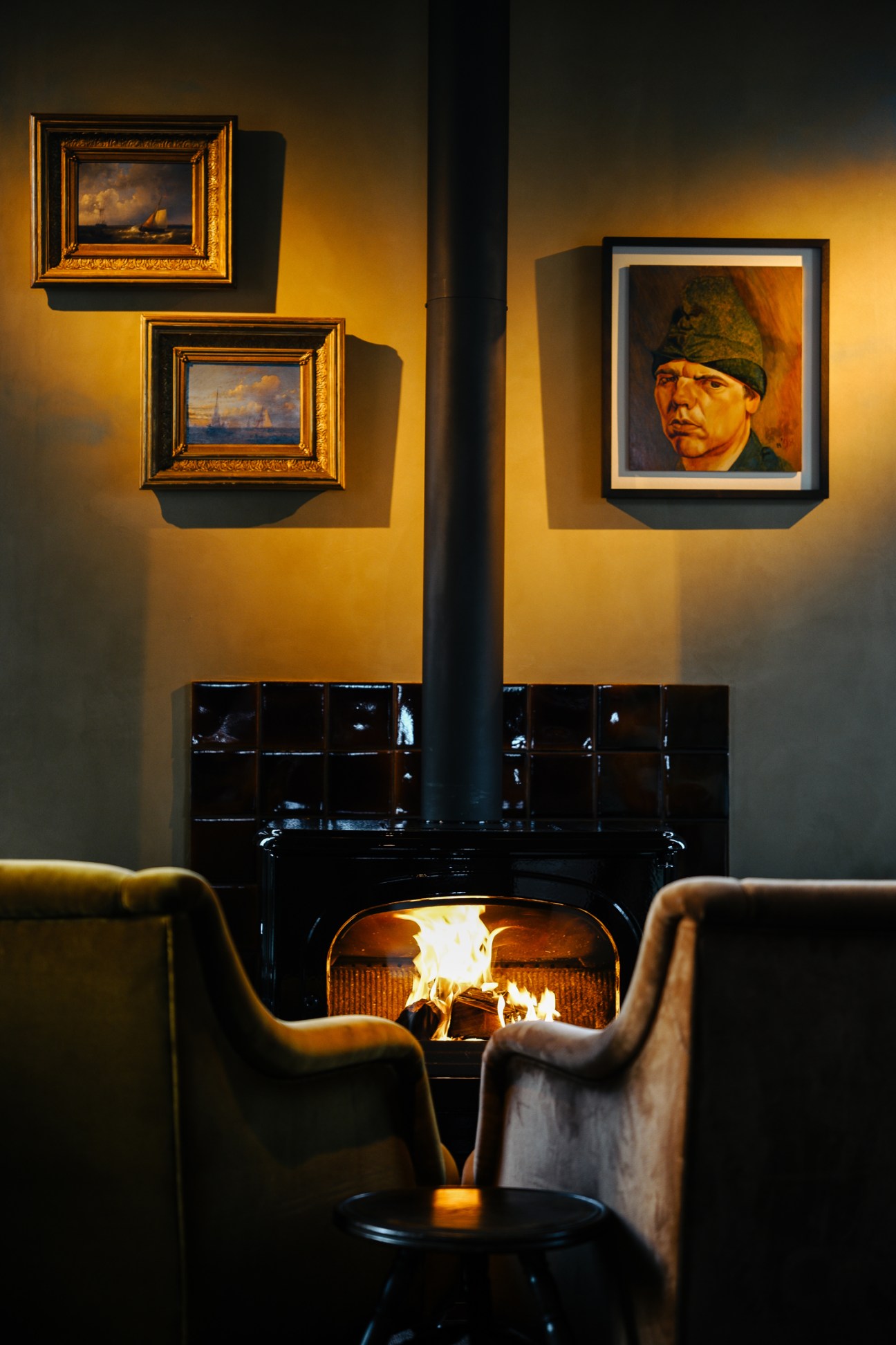 Cozy fireplace seating area with framed paintings on yellow walls and modern chairs
