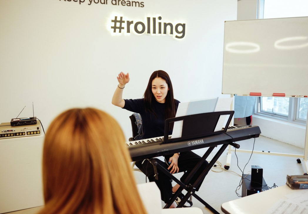Korean language teacher at keyboard instructing student in classroom at Rolling Korea language school