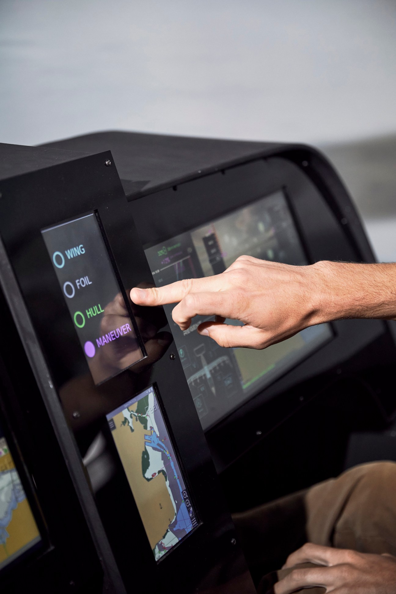 Hand touching touchscreen controls showing Wing, Foil, Hull, and Maneuver options in Regent's sea glider cockpit simulator