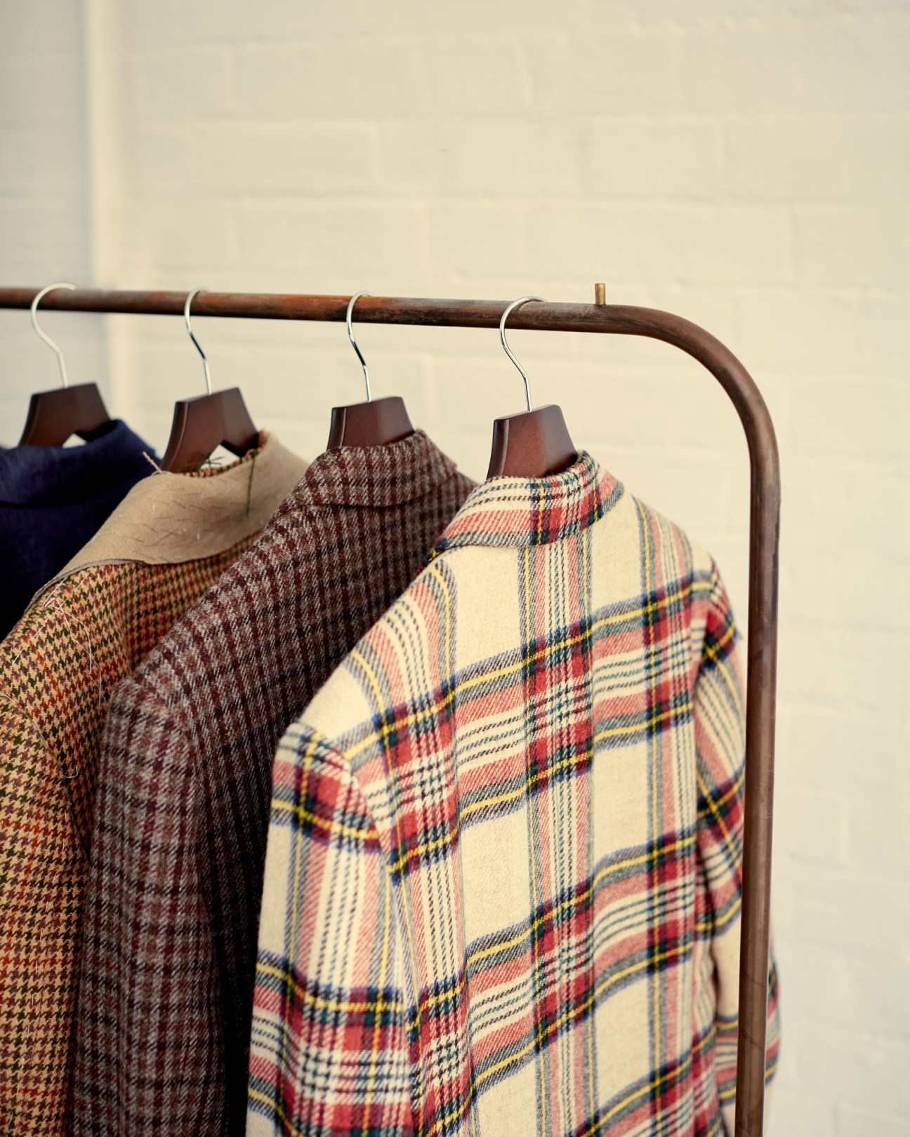 Display of tailored suits hanging in Fred Nieddu's studio showing various fabrics and cuts