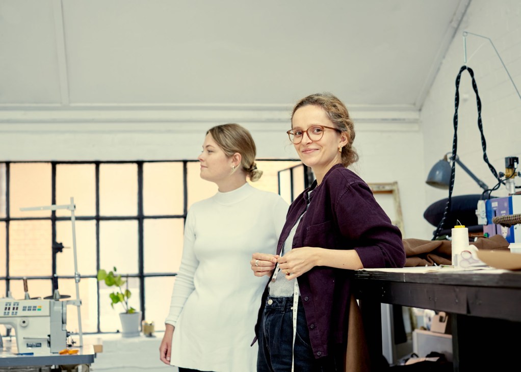 Two women working on tailoring projects at workbenches in Fred Nieddu's Shoreditch studio.