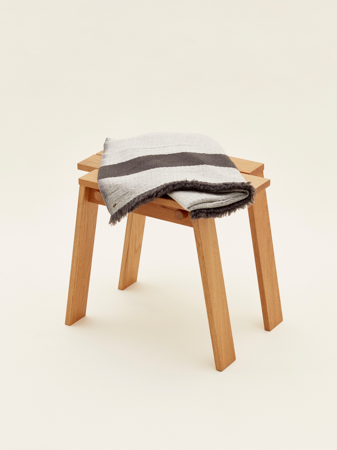 Wooden stool with striped merino wool throw draped over it