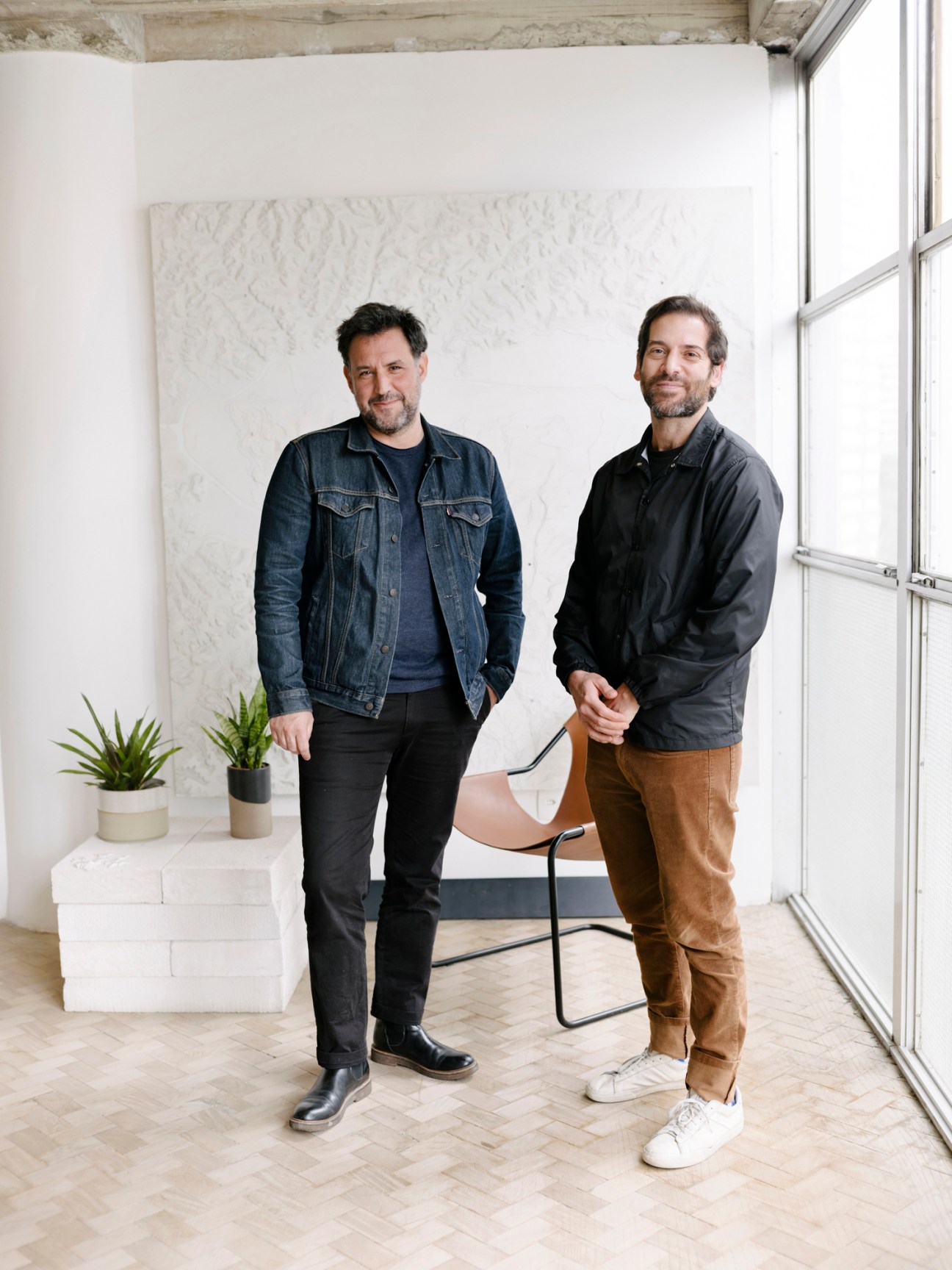 Martin Corullon and Gustavo Cedroni standing in modern concrete office space with large windows