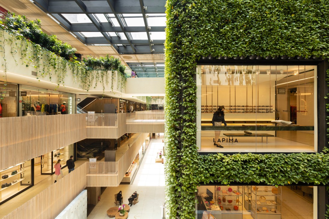 Modern multi-level shopping center with living green walls, glass ceiling, and natural lighting