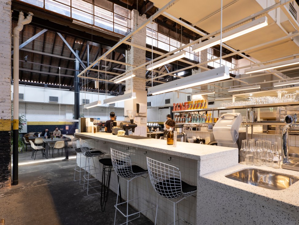 Industrial-style restaurant interior with exposed concrete, open kitchen and casual dining setup