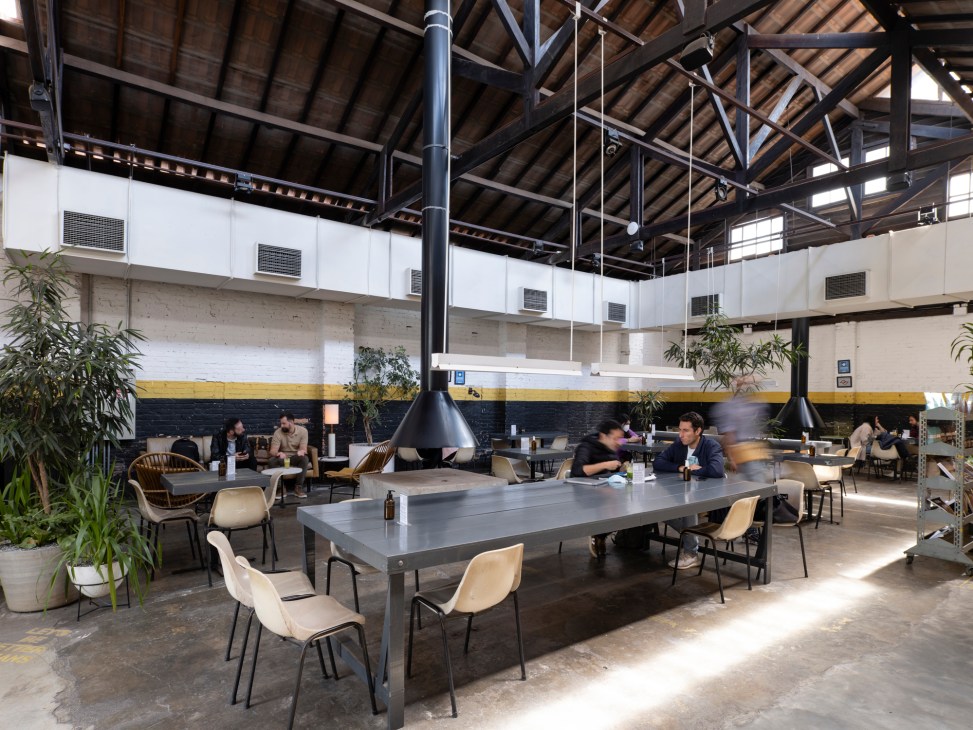 People having coffee and conversation in a bright modern café space with large windows