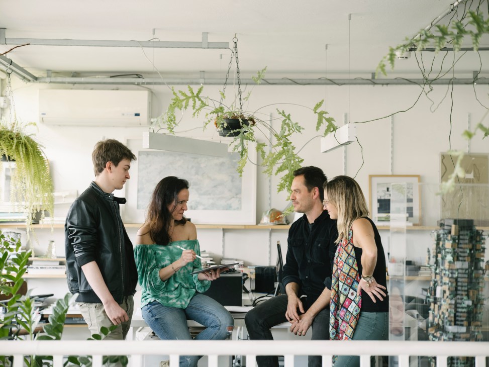 Group of architects in casual discussion in a modern office with concrete walls and large windows
