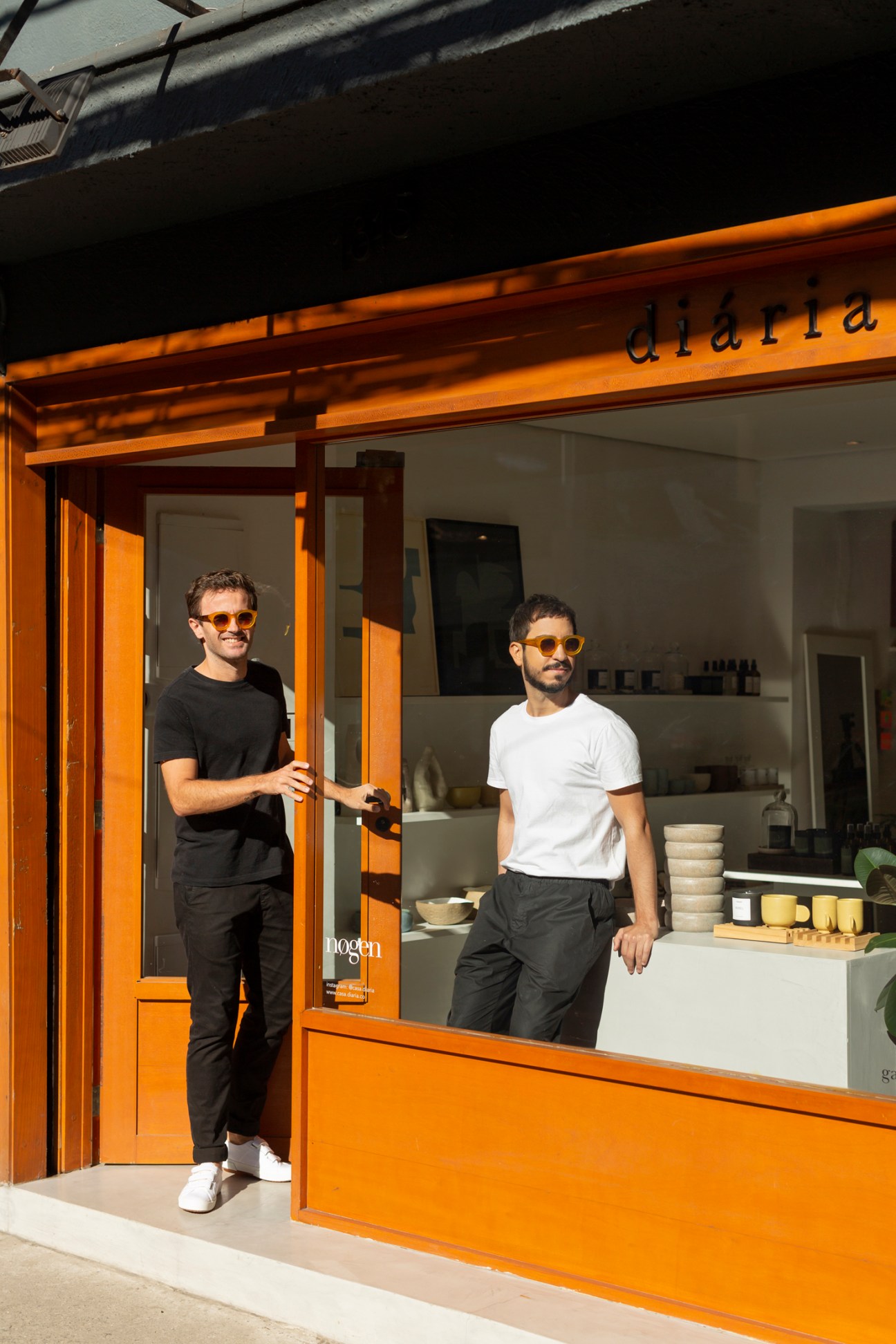 Raphael Dias and Raffaele Asselta standing outside their Diária store in São Paulo wearing sunglasses