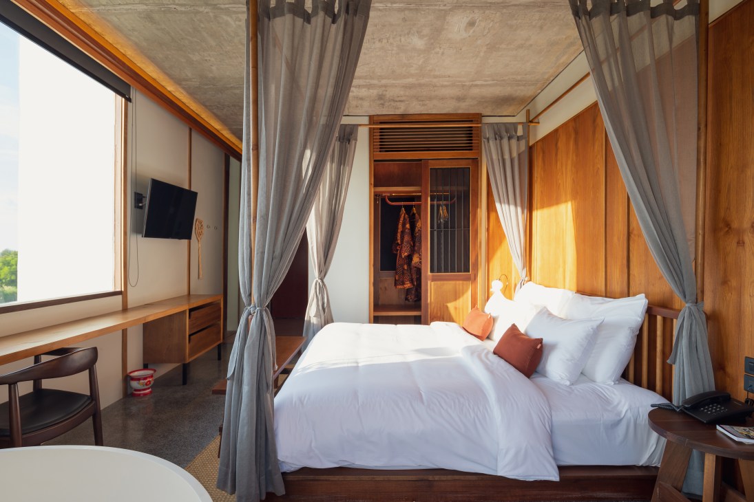 Hotel room with four-poster bed, grey curtains, wooden furniture and wardrobe at Hotel Gahn