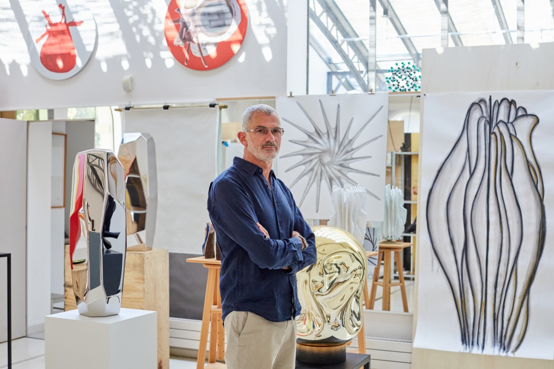 Arik Levy stands in his bright studio space surrounded by metallic sculptures and art pieces