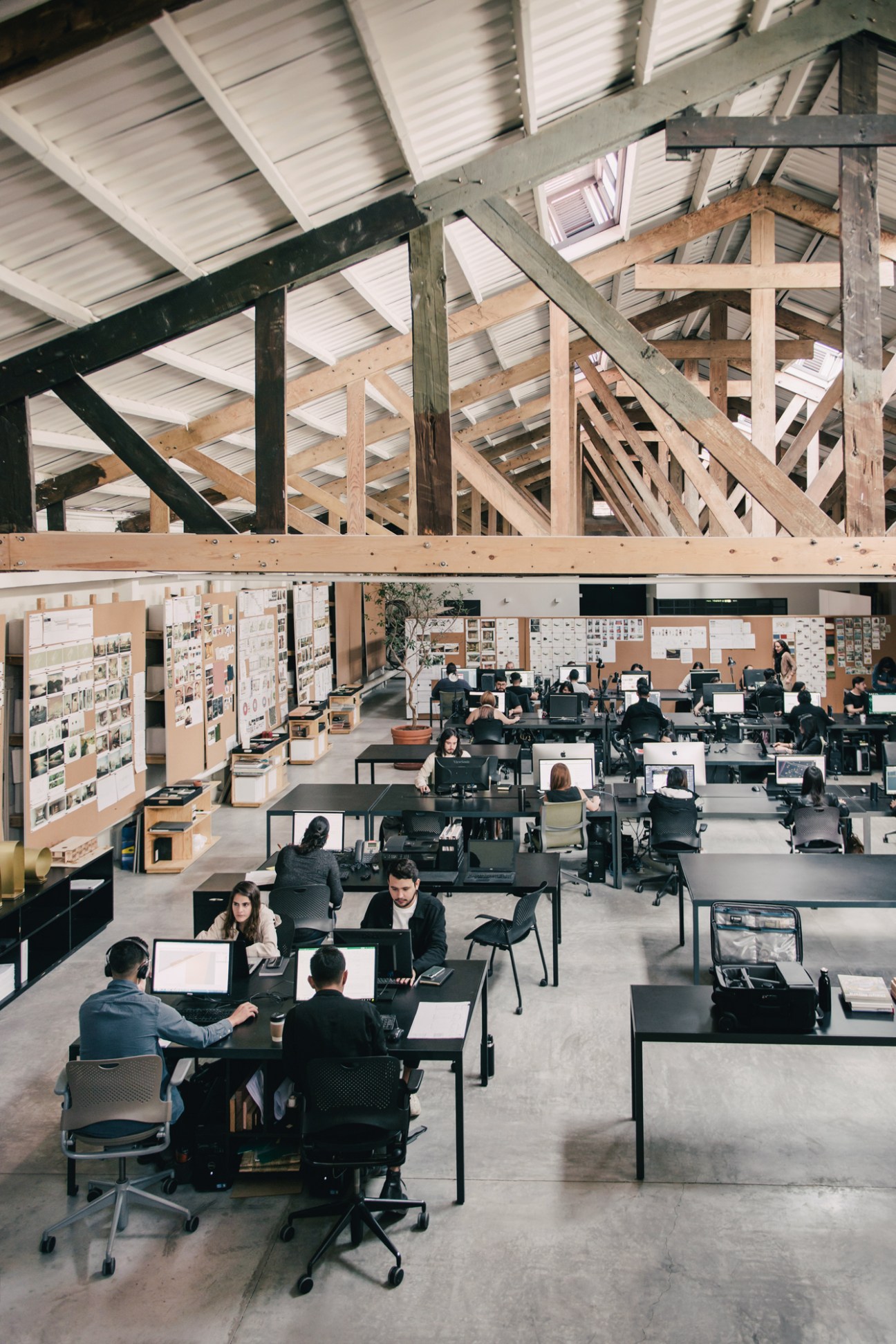 Overhead view of Esrawe Studio workspace with restored metal ceiling beams and wooden trusses.