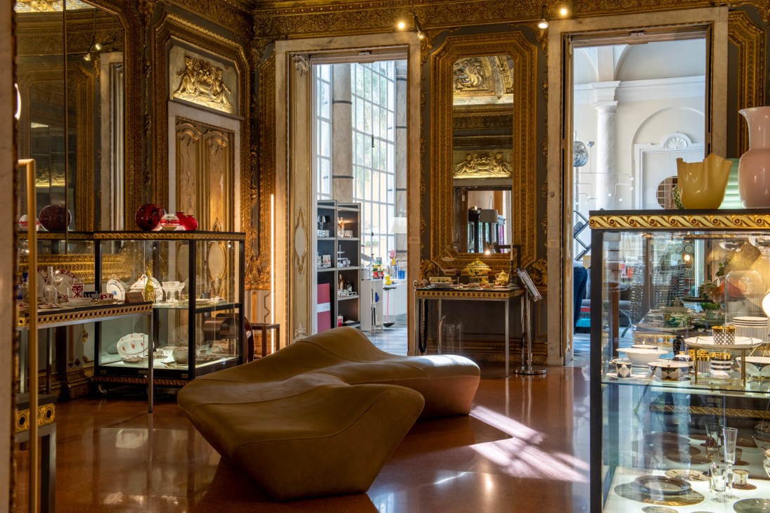 Ornate interior of Via Garibaldi 12 design shop with gilded walls, display cases, and modern sculptural seating
