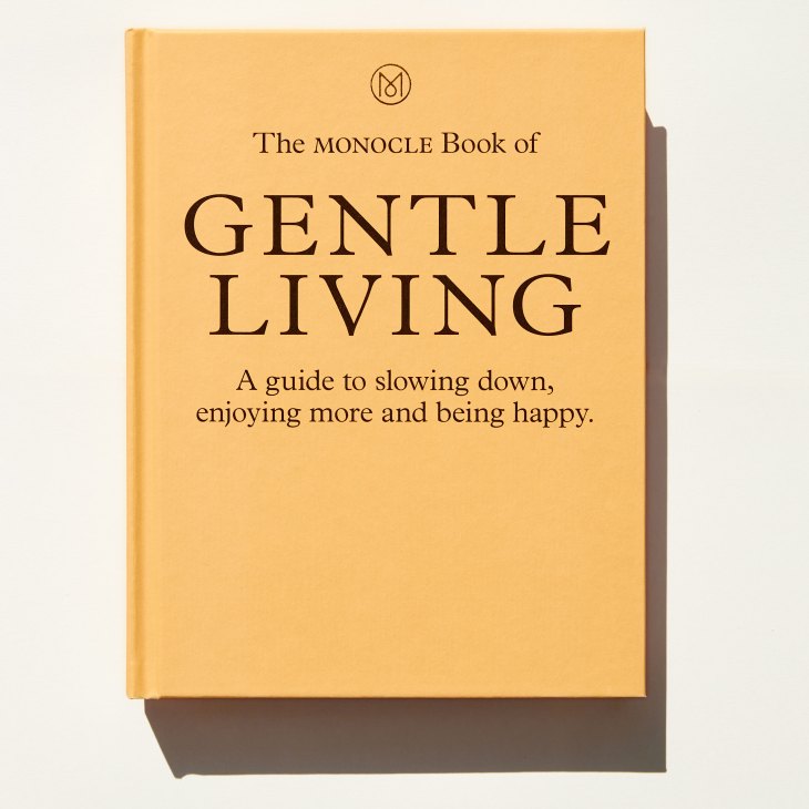 Yellow hardcover book titled 'The Monocle Book of Gentle Living' with subtitle about slowing down and being happy