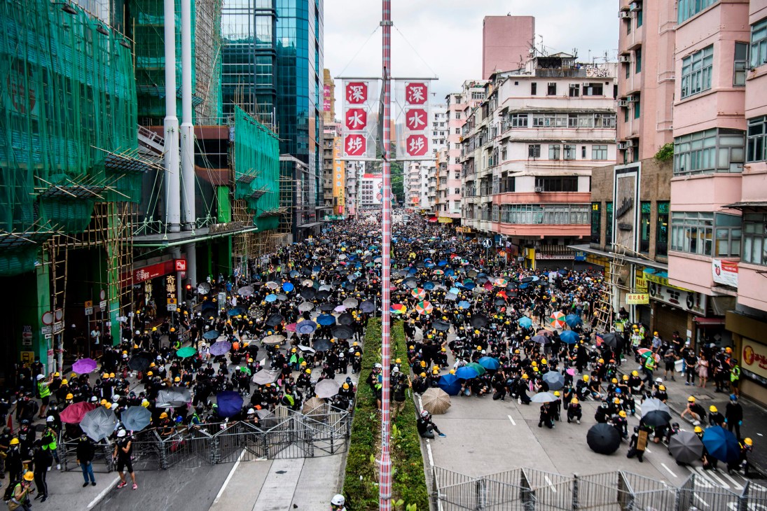 Thousands of protesters march through Hong Kong streets carrying umbrellas and signs in 2019