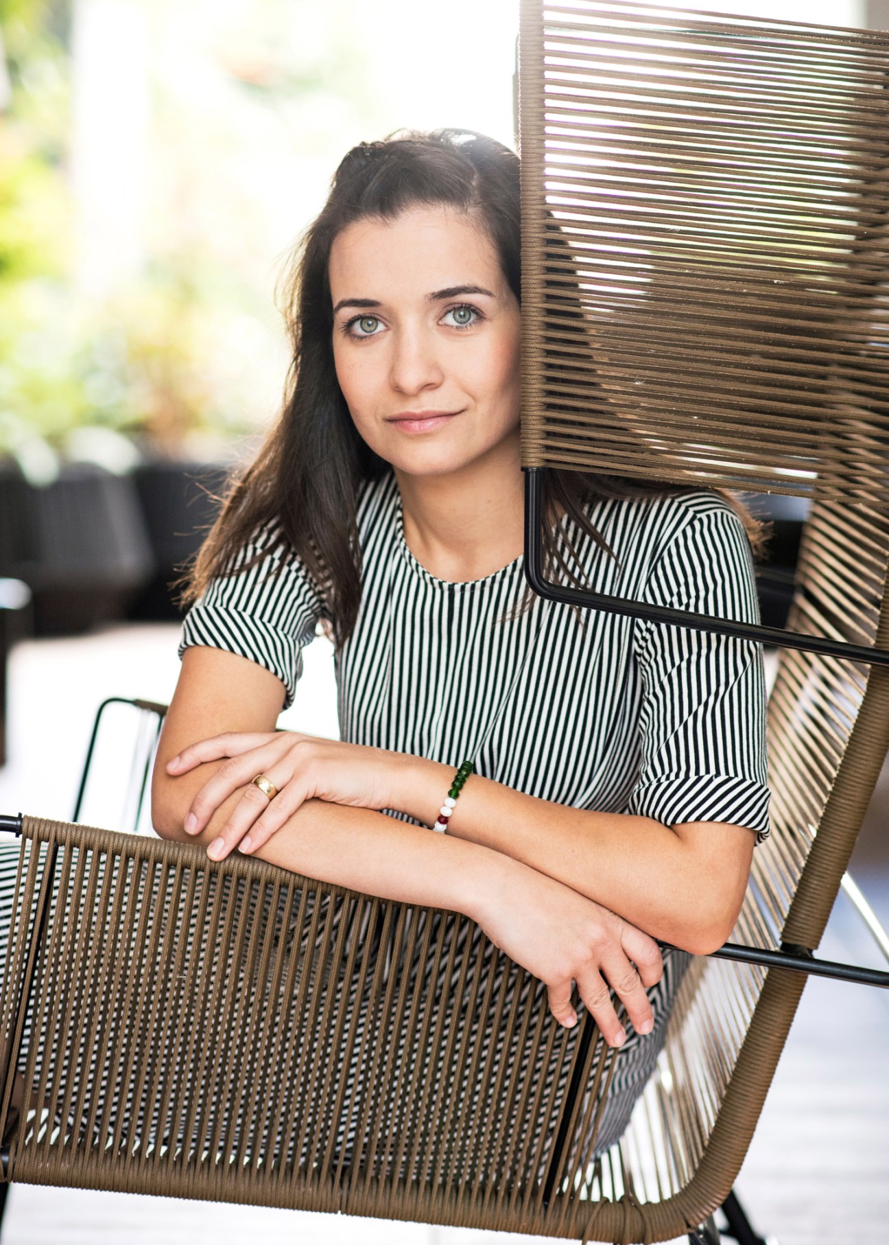 Woman in striped shirt sitting in wicker chair outdoors