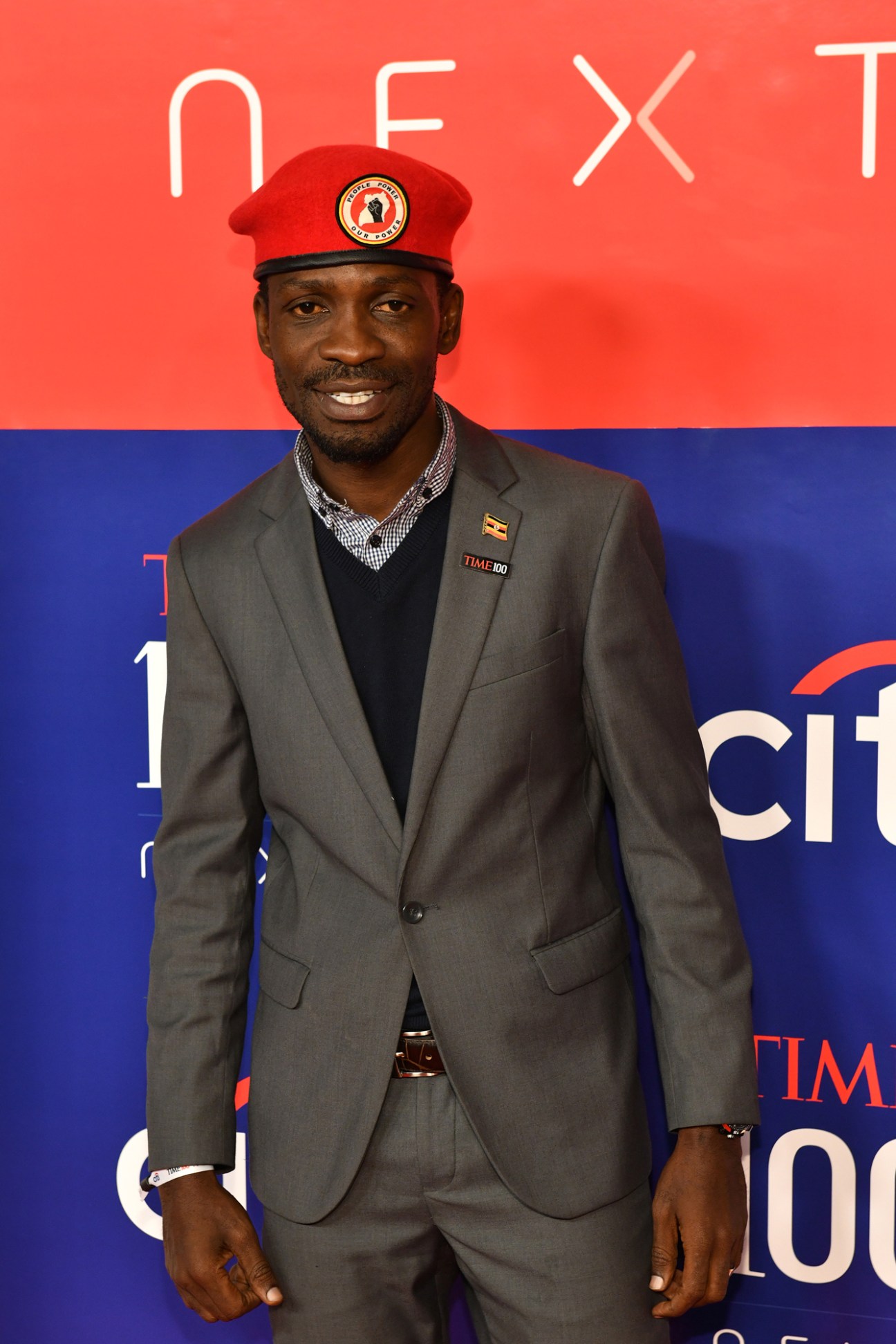 Man in grey suit and red cap at TIME 100 event backdrop