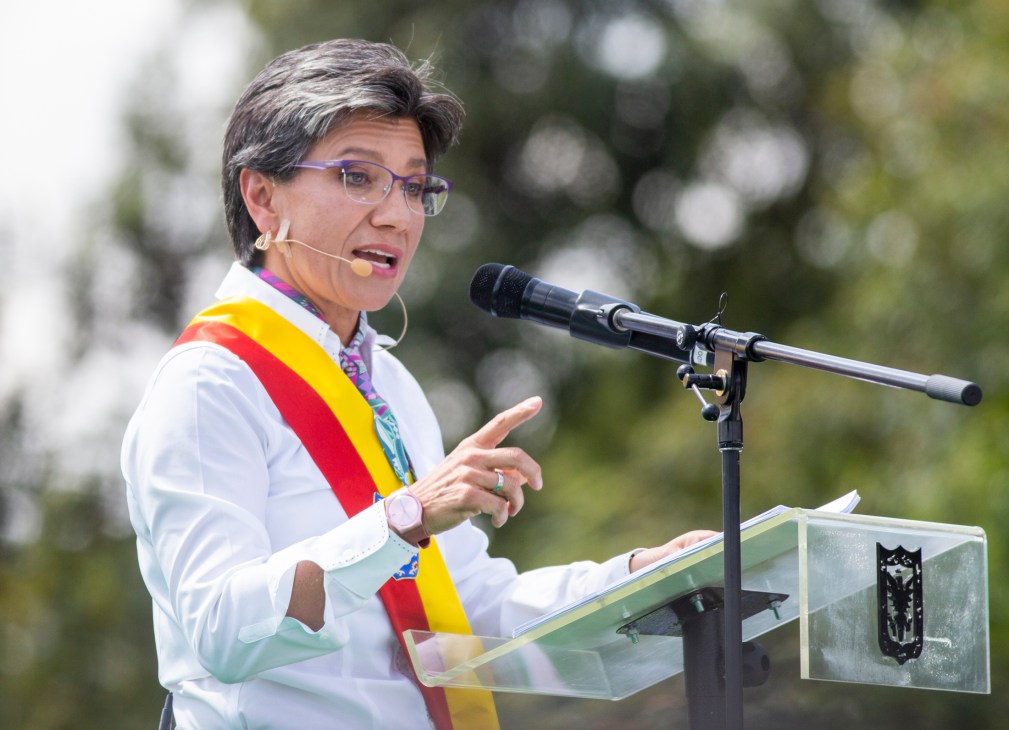 Claudia López Hernández speaking at podium wearing Colombian presidential sash