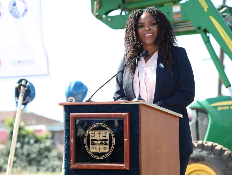 Woman speaking at a podium at an outdoor civic event.