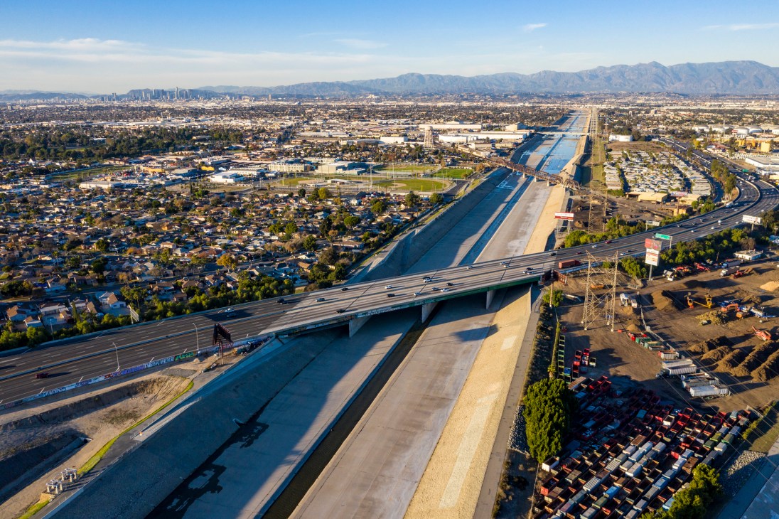 Aerial view of concrete Los Angeles River channel with highway bridge crossing over it