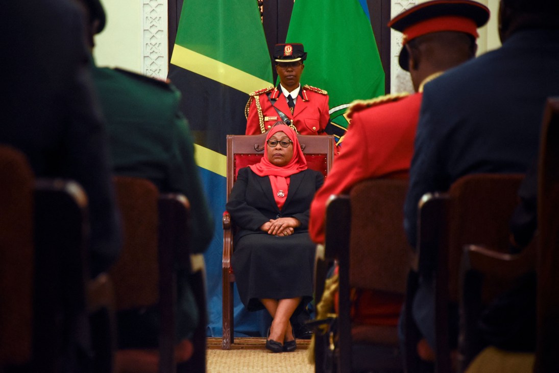 Samia Suluhu Hassan, Tanzania's first female president, sits formally in official dress before the Tanzanian flag.