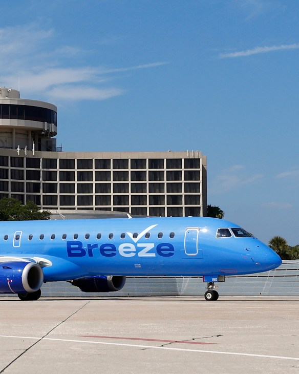 Blue Breeze Airways aircraft parked on airport tarmac with terminal building in background.
