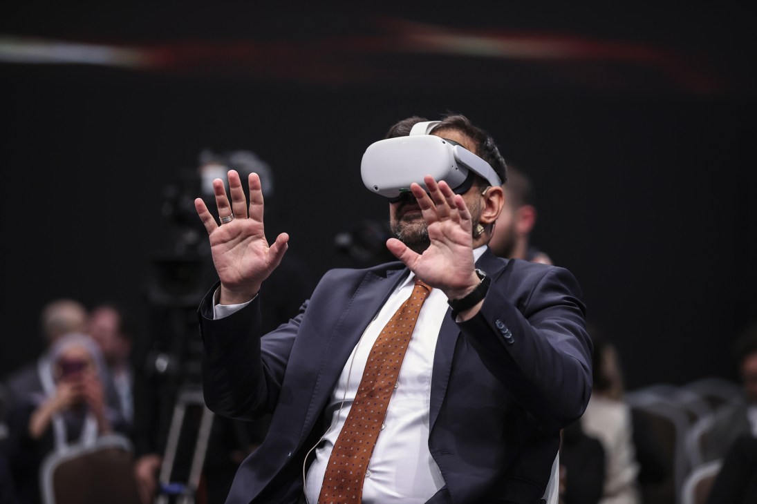Man in business suit wearing white VR headset with hands raised interacting with virtual interface