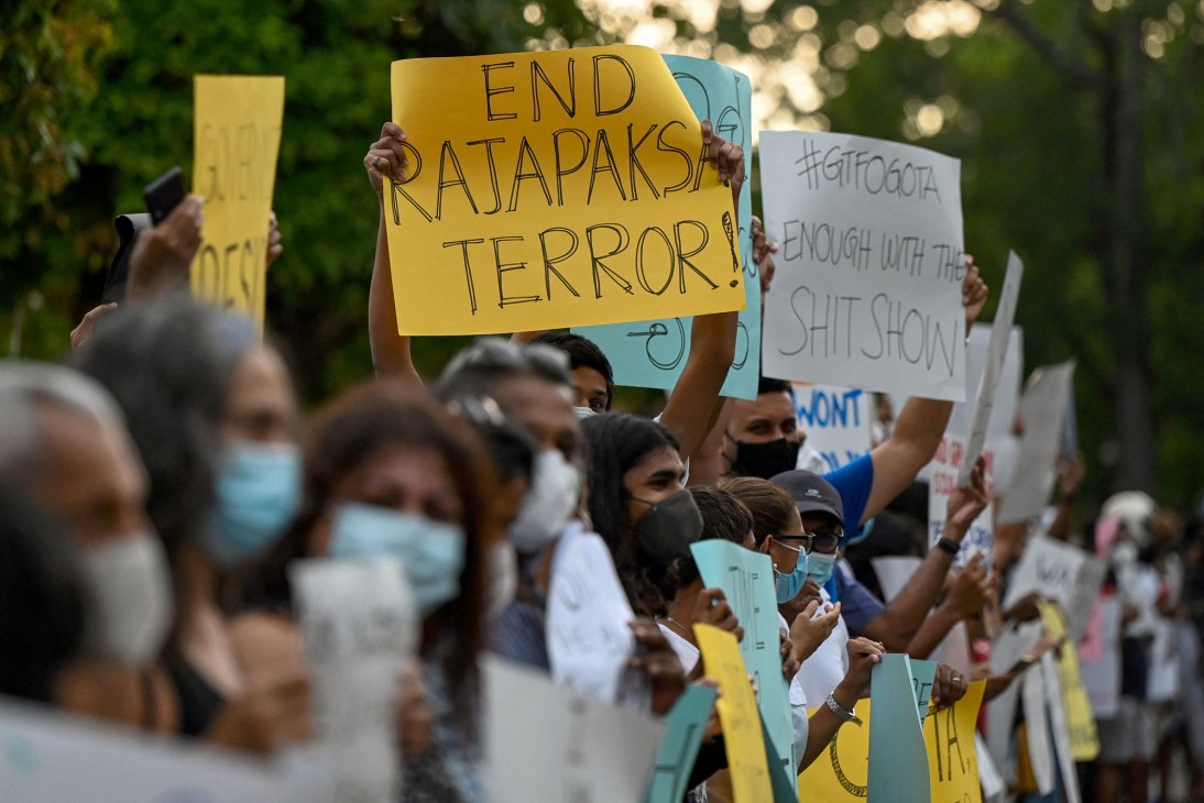 Protesters holding signs including 'END RAJAPAKSA TERROR!' and '#GTHOME' at demonstration