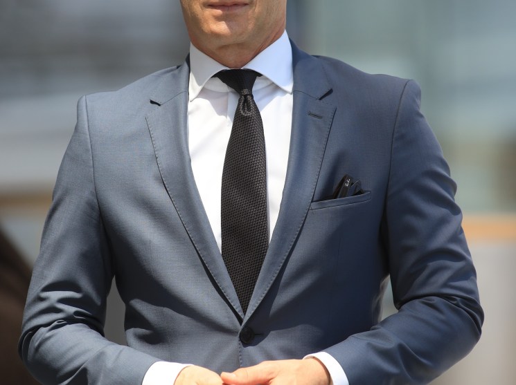 Heiko Maas in a grey suit and dark tie standing with hands clasped