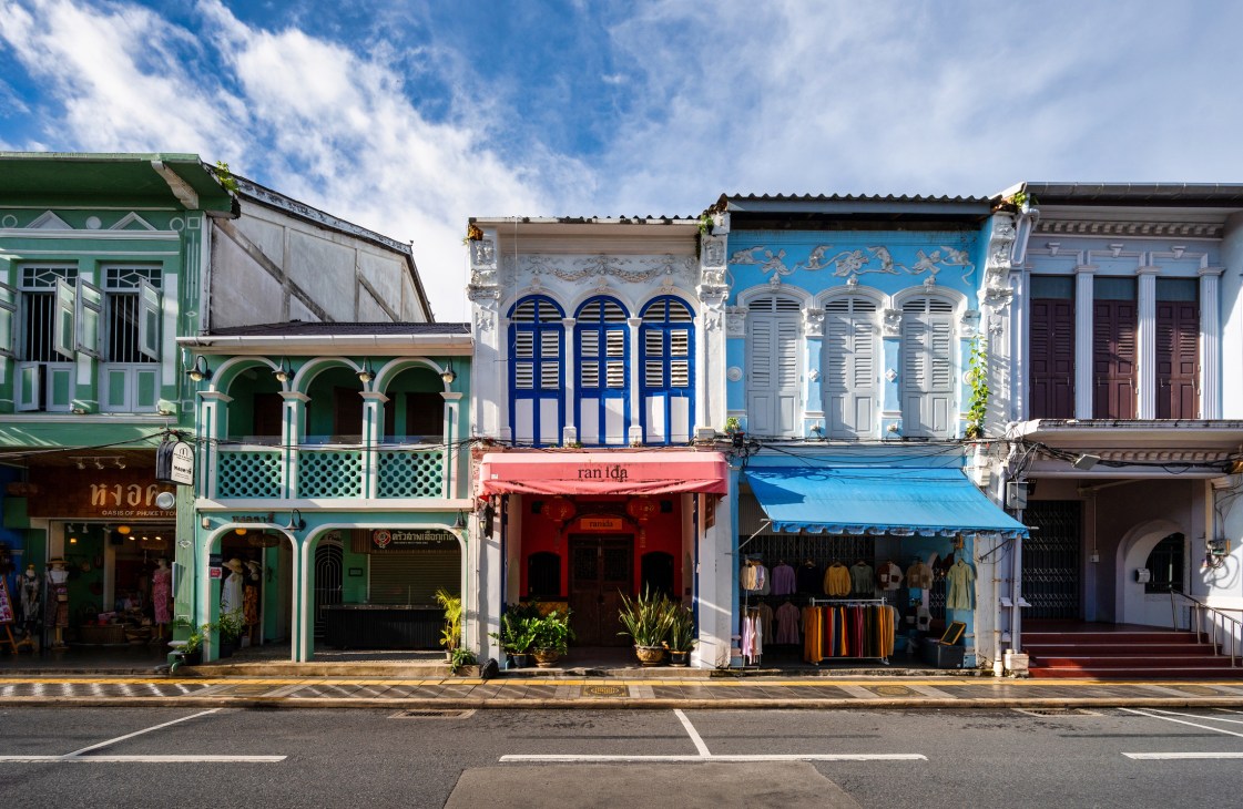 Row of colorful Peranakan shophouses with green, blue and white facades in Phuket's Old Town.