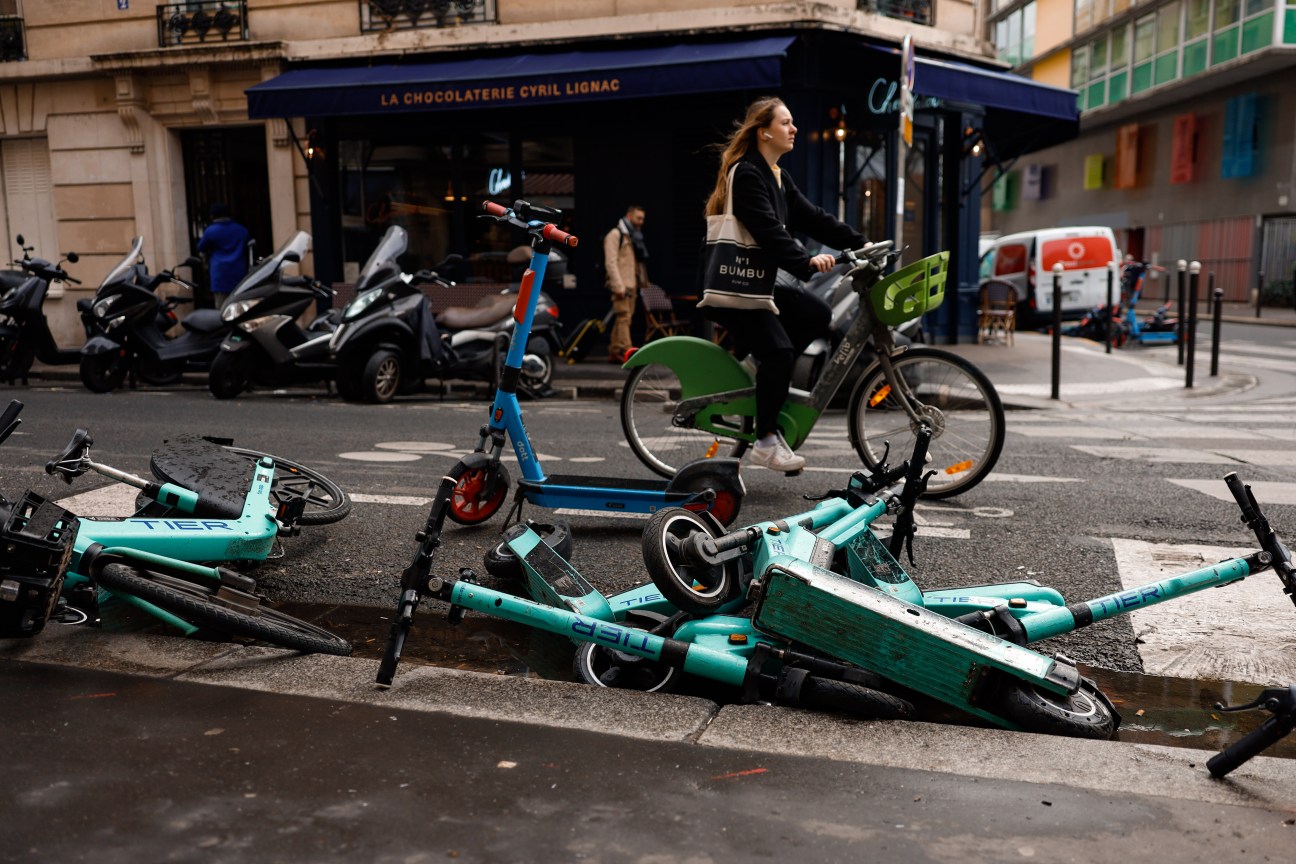 E-scooters scattered on a Paris street, abandoned in disorganized heaps on the pavement