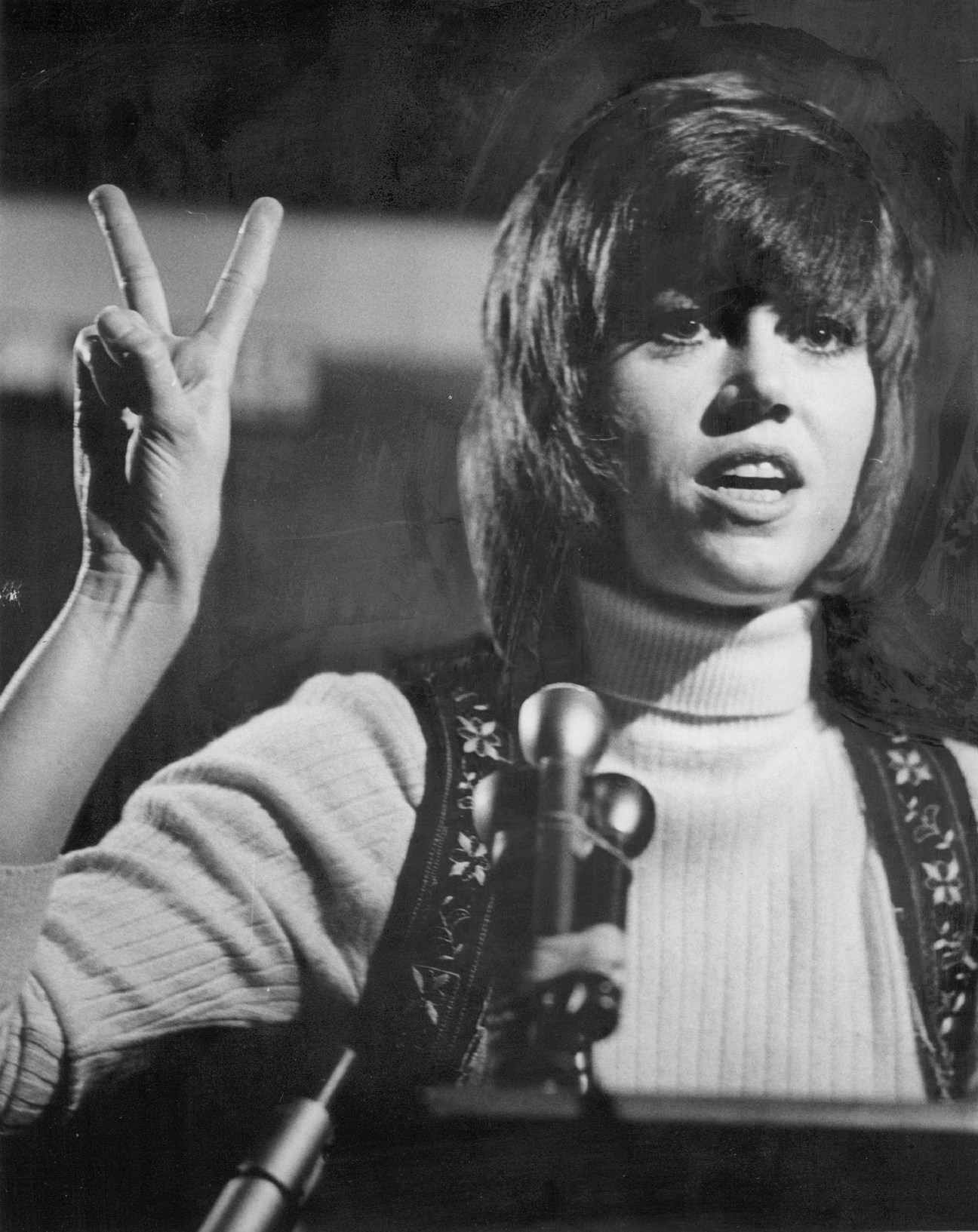 Jane Fonda at protest wearing red beret and speaking into microphone