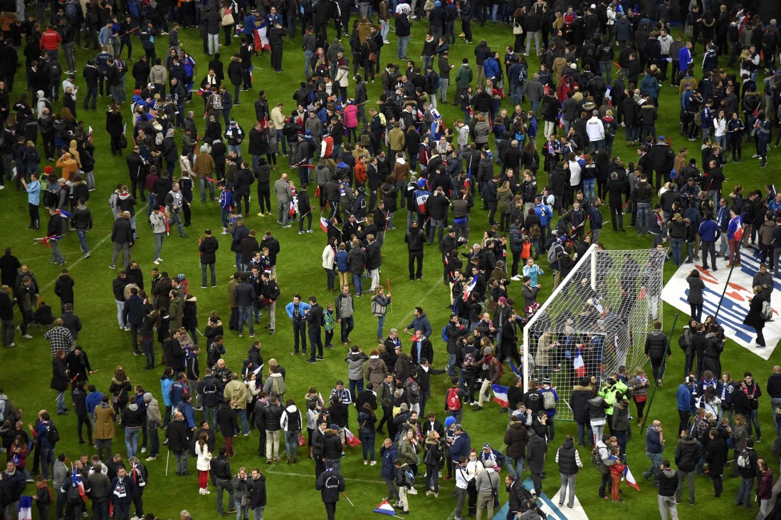 Large crowd of spectators gathered on a football pitch with goal post visible