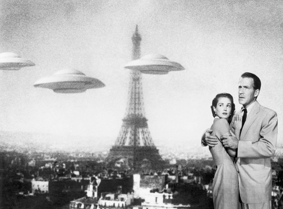 Black and white image of couple looking up at UFO flying saucers hovering over Paris Eiffel Tower