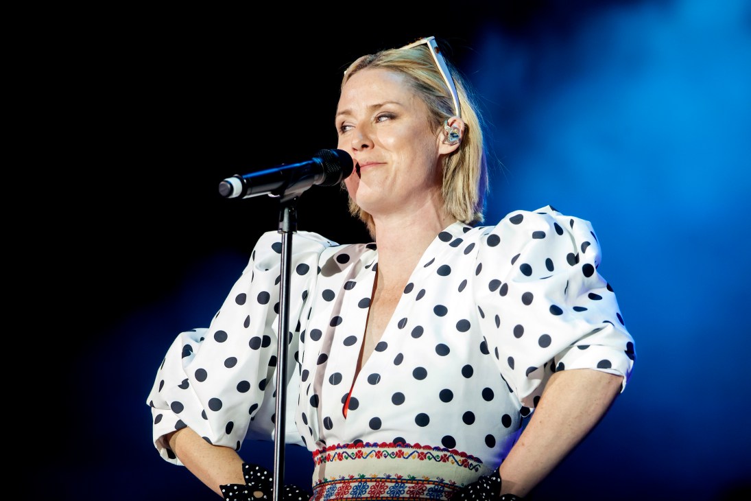 Róisín Murphy performing at a microphone wearing a white polka dot shirt with colorful patterned belt