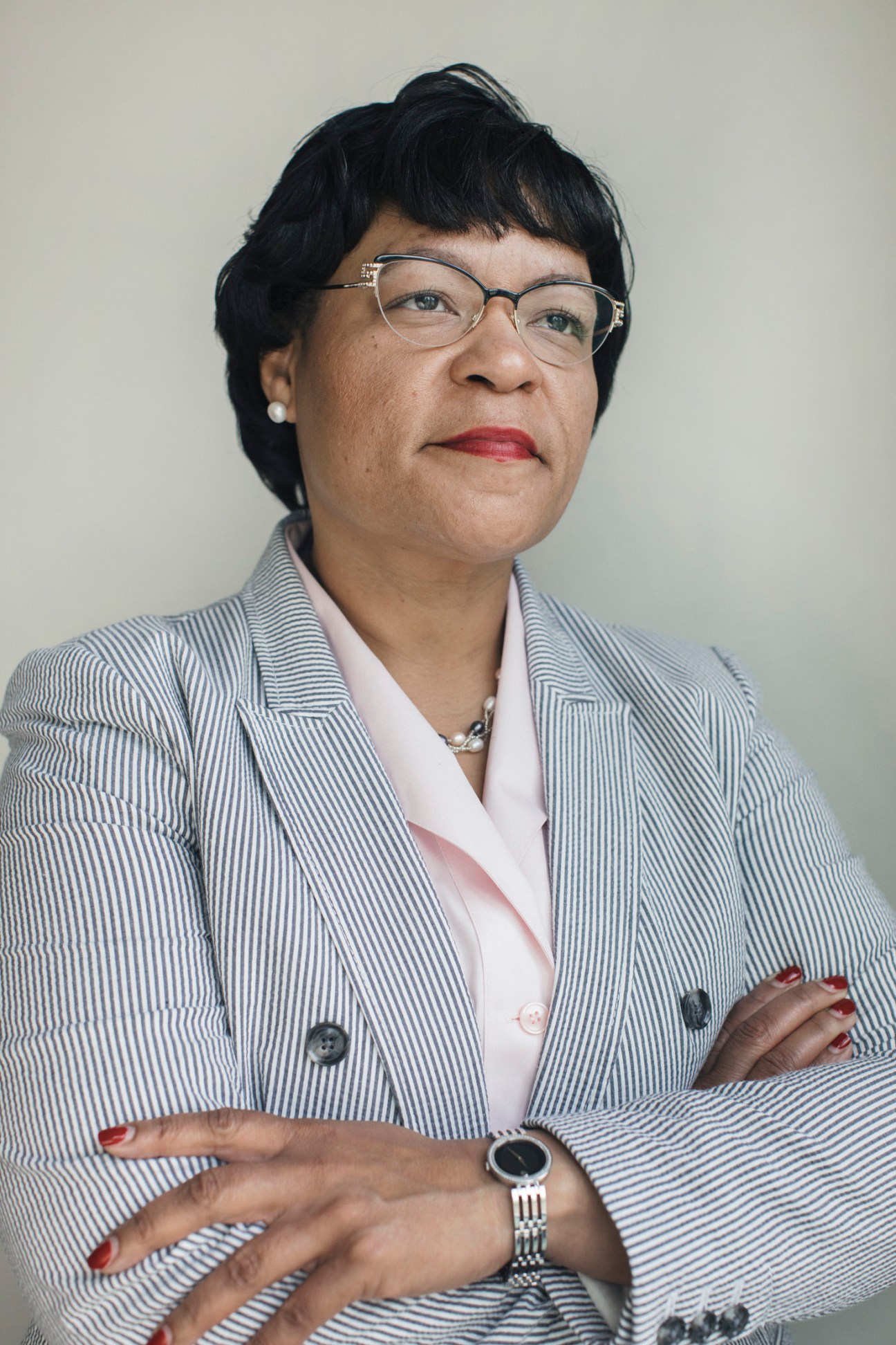 Woman in professional attire wearing glasses and jewelry, posed against a neutral background.