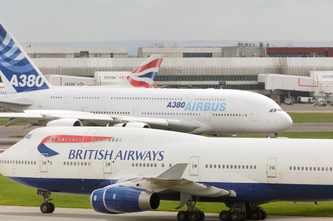 A British Airways aircraft parked next to an Airbus A380 at an airport terminal.