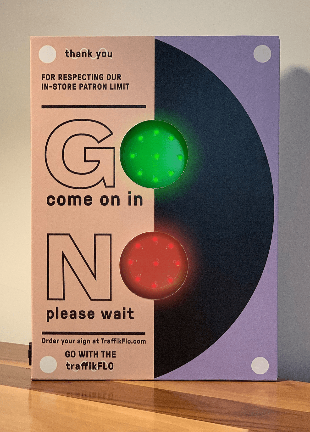 Traffikflo device with green and red lights for controlling retail customer entry, mounted on purple and pink signage